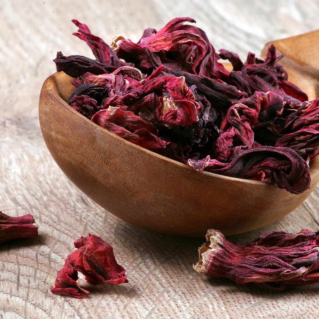 Vivid red dried hibiscus calyces (zobo) in a wooden bowl